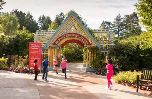 Group of children running and playing outside Backyard Discovery Gardens in the children's garden