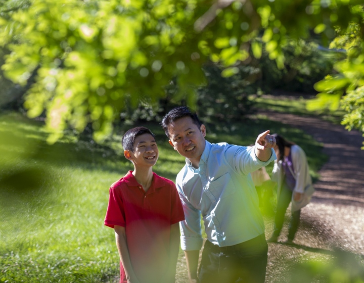 Dad with son pointing to a tree on a chipped trail