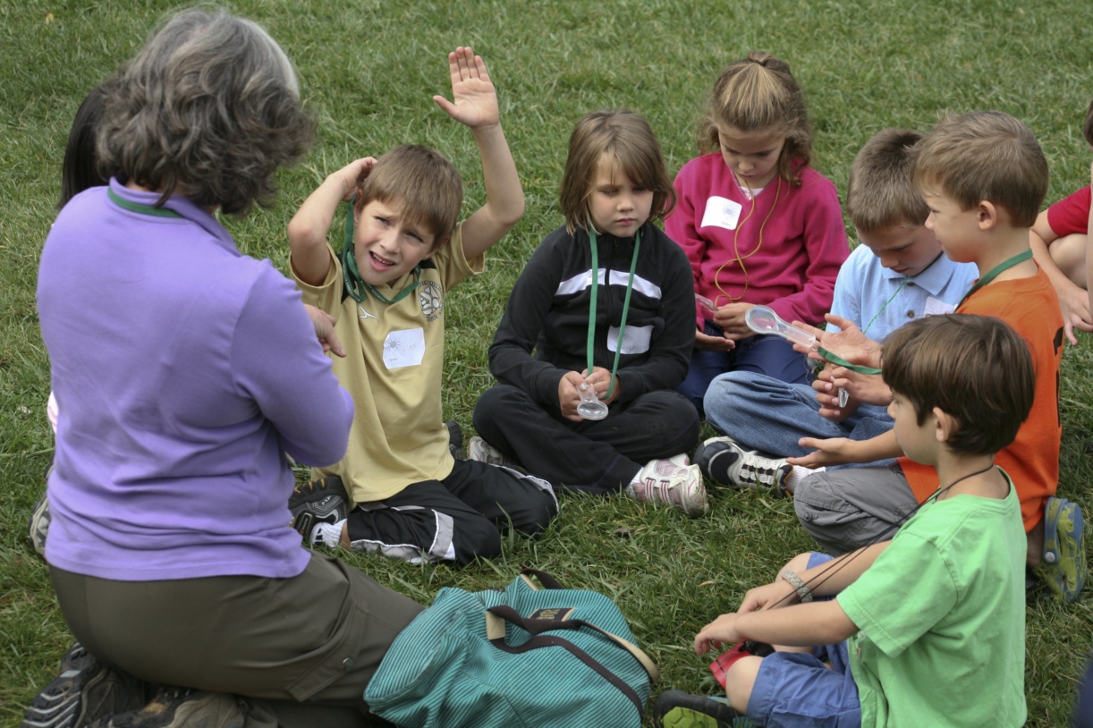Young students seated on the ground with teacher