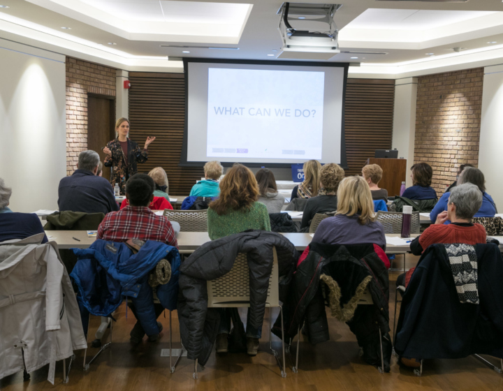 A staff member presents to an audience at a symposium